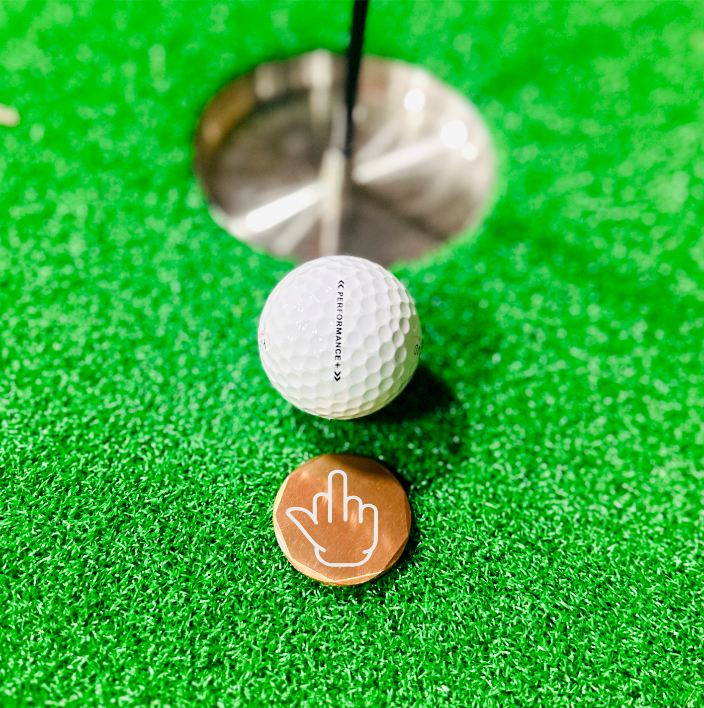 Copper golf ball marker with middle finger engraving, adds humor to any golf game.